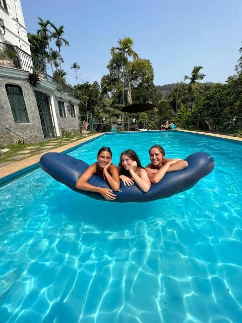 Three travellers smiling together on a pool float at the Castelo